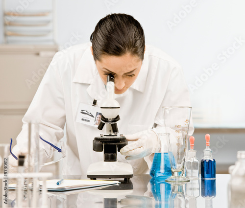 Research scientist in lab coat looking at specimen in laboratory