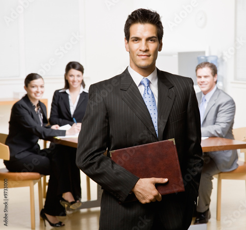 Foto: Businessman with notebook and co-workers in conference room Businessman with notebook and co-workers in conference room