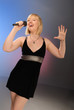 cute blond girl singing with microphone on stage