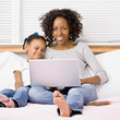 Photo: Mother and daughter typing on laptop on bed in bedroom Mother and daughter typing on laptop on bed in bedroom
