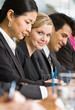 Multi-ethnic co-workers writing at conference table