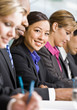 Multi-ethnic co-workers writing at conference table