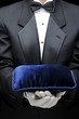 Butler holding a velvet pillow in front of his torso