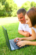 caucasian couple using laptop outdoor in park. love and family
