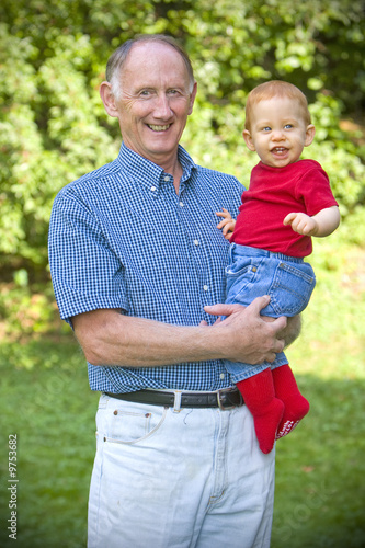 Photo: Grandfather holding happy grandson in sunny garden Grandfather holding happy grandson in sunny garden