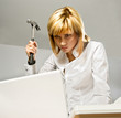 Photo: Angry business lady hitting a laptop with a hammer. Angry business lady hitting a laptop with a hammer.