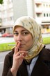 Lächelnde Frau mit Kopftuch und Zigarette
