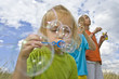 Children blowing bubbles on summer meadow