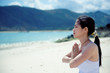 young asian woman meditating on the beach