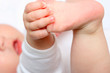 new born babyholding a foot with a hand