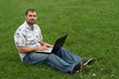 Photo: Boy working on laptop sitting on grass. Boy working on laptop sitting on grass.