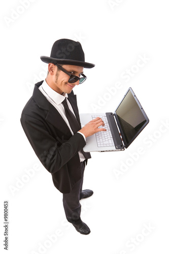 Photo: funny looking computer hacker with laptop on white funny looking computer hacker with laptop on white