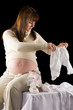 happy pregnant woman portrait with baby clothes in hands