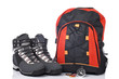 Hiking boots, compass, and backpack over a white background
