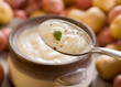Freshly made warm potato soup on a spoon in front of a full bowl Freshly made warm potato soup on a spoon in front of a full bowl