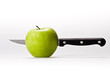 Green apple with a knife inside on white background