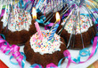 Birthday brownies with 2 lit candles and decorations.