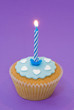 Single cupcake with blue lit candle and icing