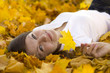 smiling woman laying on falling leaves smiling woman laying on falling leaves