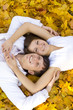 happy couple laying on yellow leaves