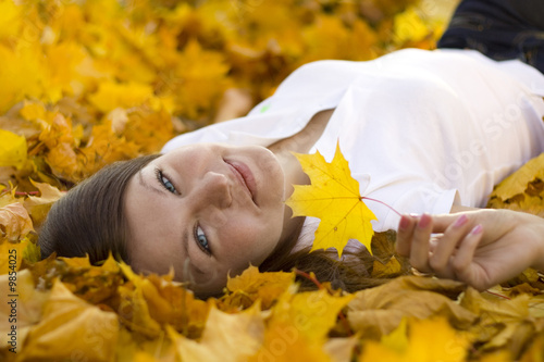 Photo: smiling woman laying on falling leaves smiling woman laying on falling leaves