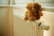 Two teddy bears on top of the heater or thermoregulator.