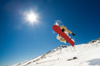 Snowboarder jumping through air on blue sky background