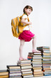 View from aside of smart girl going upwards on book stairs