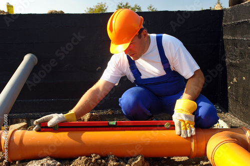 Photo: Plumber measuring slope of assembled sewage pipes Plumber measuring slope of assembled sewage pipes