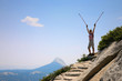 Happy young woman standing  on top of a mountain with arms rised