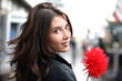 Beautiful woman with red flower looking back. Shallow DOF.