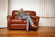 Senior woman sitting on leather sofa at home Senior woman sitting on leather sofa at home