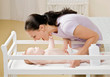 Devoted mother playing with baby on changing table