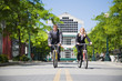 Two business people riding bicycle to work saving gas