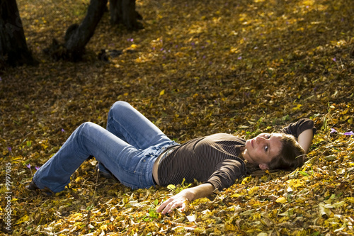 Foto: Young woman laying in autumn forest Young woman laying in autumn forest