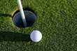 A white golf ball near the hole of a golfing green or course