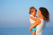 Mother keeps child at hands of edge of sea