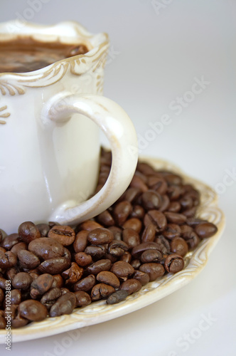 Cup of coffee and whole coffee beans on a plate