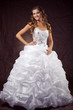 Fashion model wearing wedding dress at brown studio background