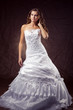 Fashion model wearing wedding dress at brown studio background