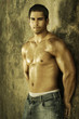 Young muscular male against wall with golden light
