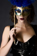 Beautiful young woman holding a carnival mask wearing catsuit