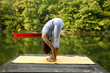 Woman doing yoga on lake in park in autumn