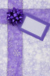 Purple ribbon and blank gift tag on snowflake background
