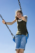 Photo: A young teen girl on a playground swing in front of a blue sky A young teen girl on a playground swing in front of a blue sky