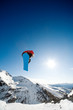 Snowboarder jumping through air on blue sky background