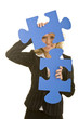 Blonde Frau schaut durch zwei große blaue Puzzleteile
