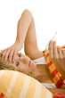 Frau schaut auf ein Fieberthermometer