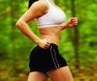 Beautiful young woman runner in a green forest.