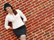 Fashionable young woman posing in front of a brick wall.